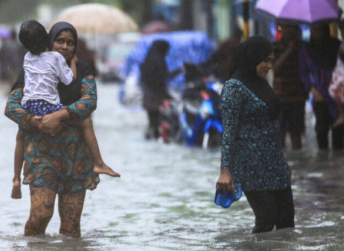 A mother and child walking through flooded streets | Photo: NDMA