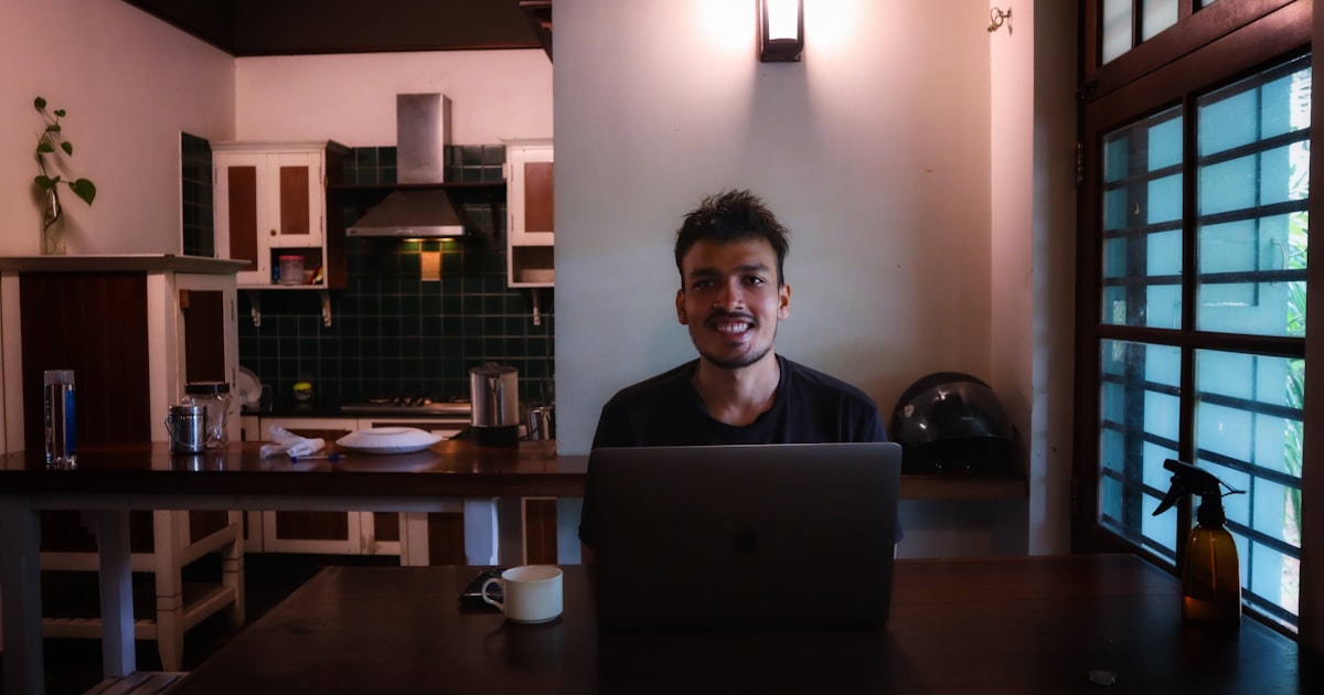 NRI professional video calling family in India from a modern apartment abroad, laptop showing matrimony profiles