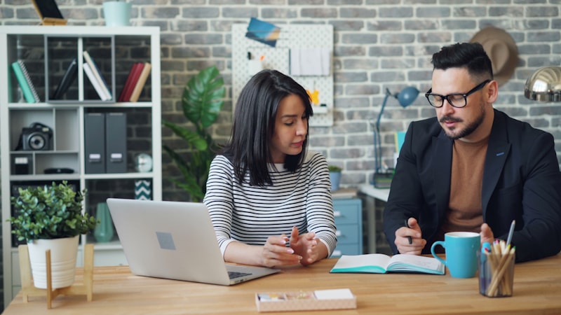 Indian couple discussing financial planning before marriage with documents and laptop on table