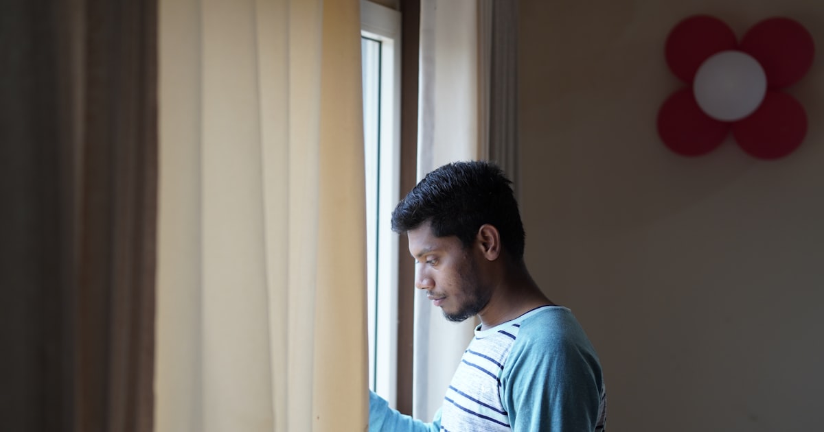 Young Indian person sitting thoughtfully by a window, reflecting on how to say no in arranged marriage
