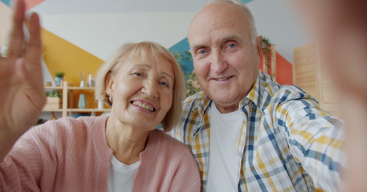 Elderly couple waving hello on a video call.