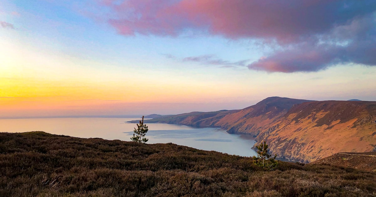 a landscape with hills and a body of water in the distance