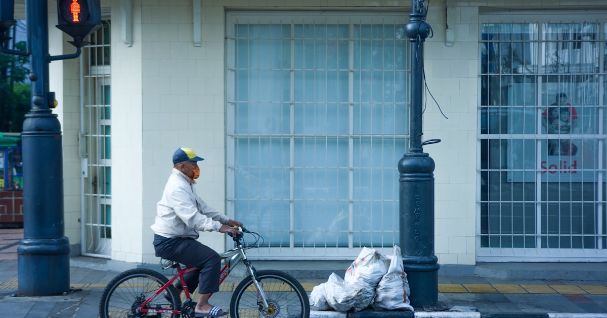 a man riding a bike down a street next to a traffic light