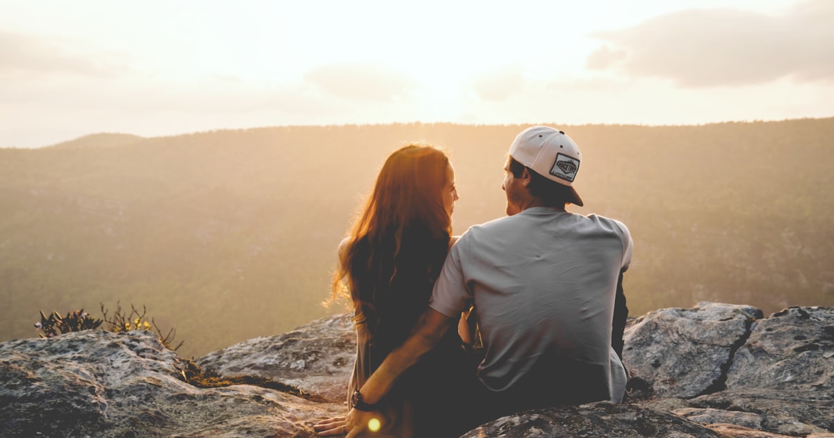 man and woman sitting on rock during daytime