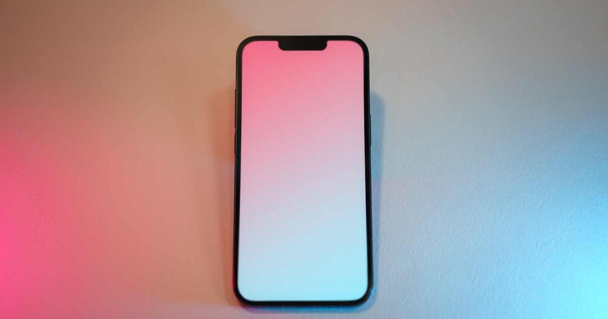 A pink and white cell phone sitting on top of a table
