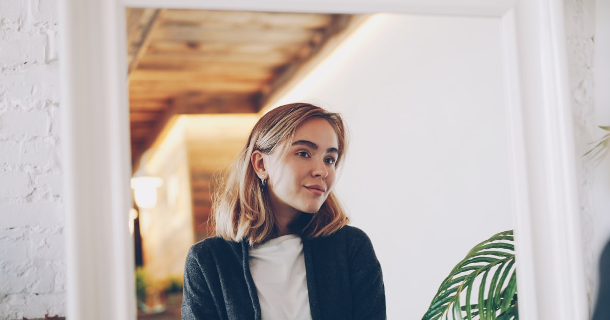 Young woman looking at her reflection in a mirror.