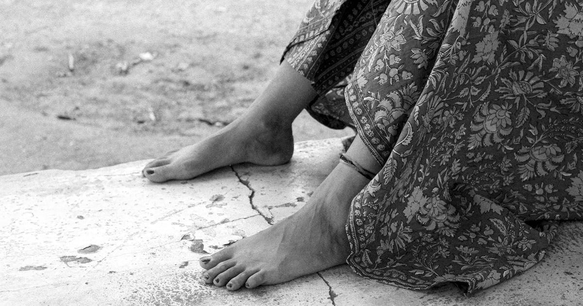 a woman's bare feet sitting on a concrete slab
