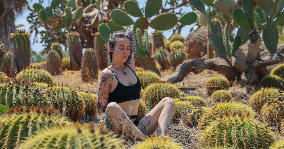 woman in black tank top sitting on green grass field during daytime