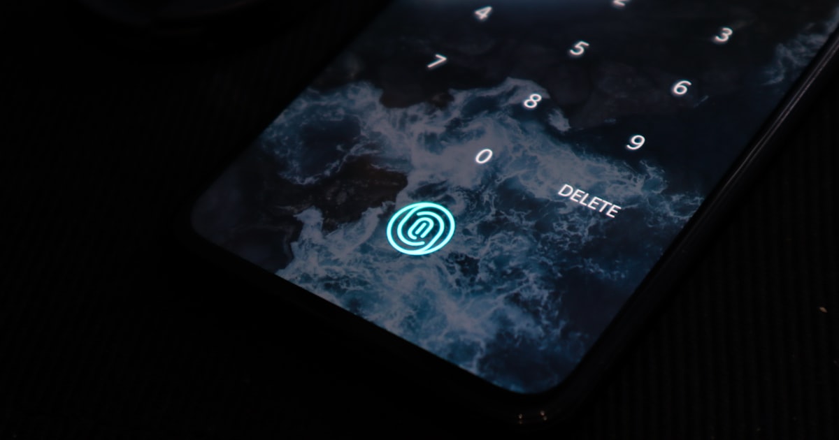 Close-up of a smartphone screen showing settings toggles with a lock icon, warm ambient lighting